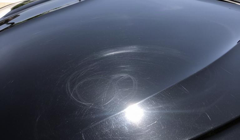 沖縄の屋外駐車場に停めた黒い高級車のボンネットに見える洗車傷とオーロラマーク